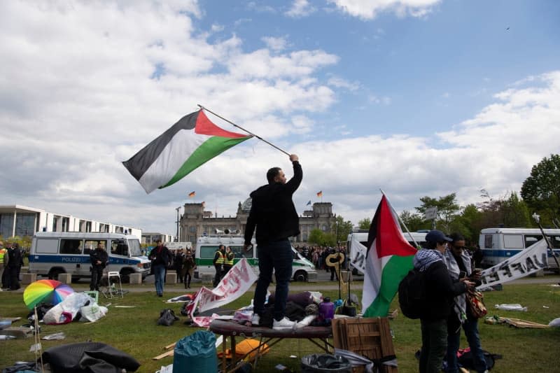 Protesters hold Palestinian flags while police officers clear the pro-Palestinian protest camp outside the German Bundestag. Paul Zinken/dpa