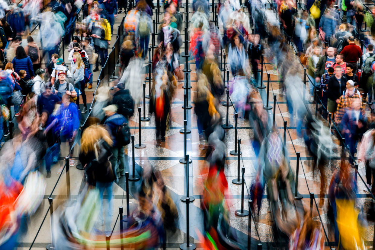 Travelers wait in line before passing through a security checkpoint at Denver International Airport.