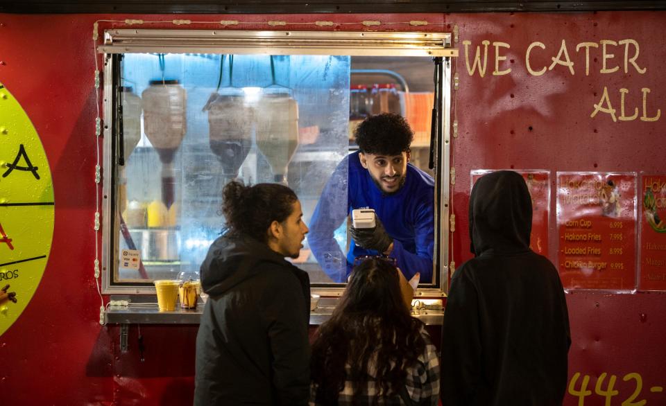 Wail Algahim, co-owner of the Hakona Matata food truck, greets customers during Ramadan Nights in west downtown Dearborn on Saturday, April 1, 2023.