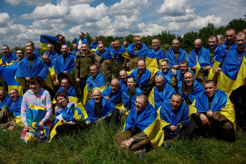 Ukrainian POWs shout slogans while they pose for a picture after a swap at an undisclosed location in Ukraine