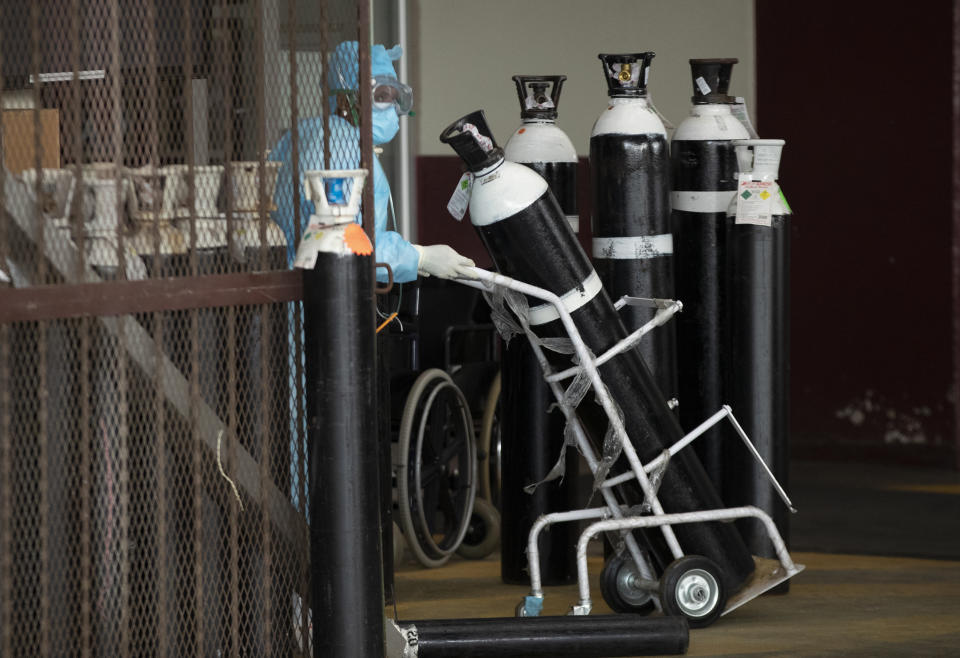 A health worker in a protective suit runs transport oxygen cylinder in a makeshift emergency units at Steve Biko Academic Hospital in Pretoria, South Africa, Monday, Jan. 11, 2021, which is battling an ever-increasing number of Covid-19 patients. (AP Photo/Themba Hadebe)