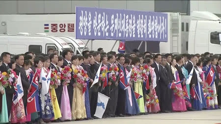 People holding North Korean and unification flags wait for South Korean President Moon Jae-in and First Lady Kim Jung-sook to arrive at Pyongyang Sunan International Airport, North Korea ahead of the third summit with North Korean leader Kim Jong Un in this still frame taken from video September 18, 2018. KBS/via REUTERS TV