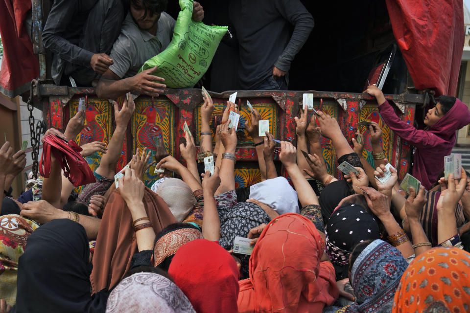 Women show their identity cards to get a free sack of wheat flour, at a distributing point, in Lahore, Pakistan, Monday, March 20, 2023. Pakistan's Prime Minister Shahbaz Sharif will provide free flour to deserving and poor families during the Muslim's holy month of Ramadan due to high inflation in the country. (AP Photo/K.M. Chaudary)