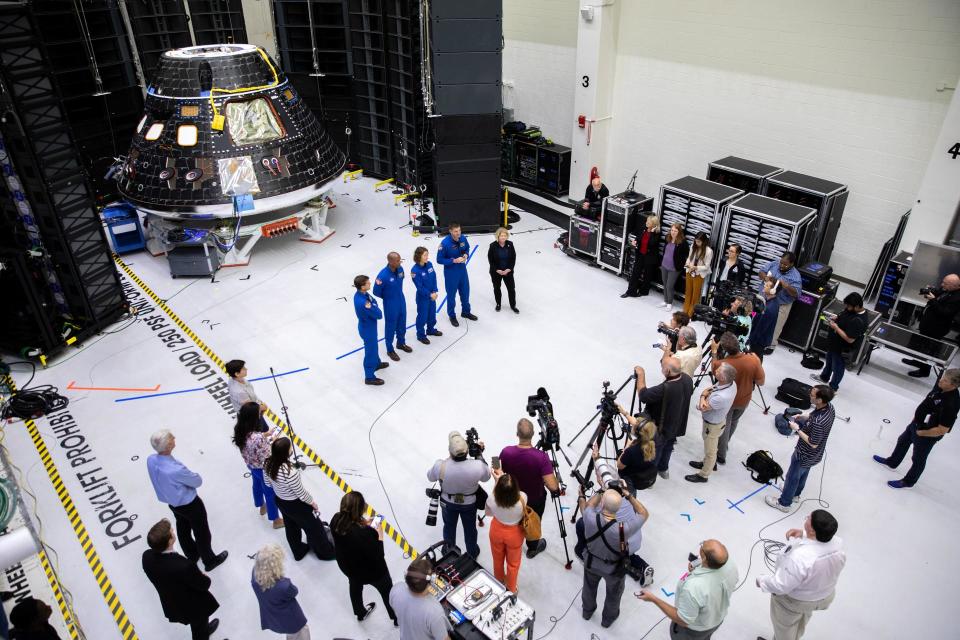 Artemis II crew members, shown inside the Neil Armstrong Operations and Checkout Building at NASA’s Kennedy Space Center in Florida, stand in front of their Orion crew module with NASA Deputy Administrator Pam Melroy during a media event on Aug. 8, 2023. From left are: Reid Wiseman, commander; Victor Glover, pilot; Christina Hammock Koch, mission specialist; and Jeremy Hansen, mission specialist.