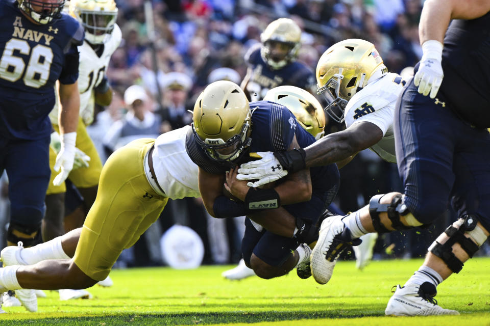 Navy quarterback Xavier Arline (7) runs the ball and dives into the end zone for a touchdown against two Notre Dame defenders during the first half of an NCAA college football game, Saturday, Nov. 12, 2022, in Baltimore. (AP Photo/Terrance Williams)