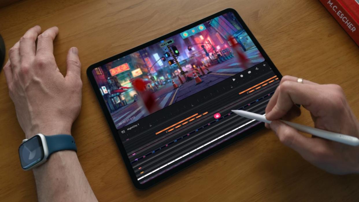  Man using iPad Pro with Apple Pencil on a wooden desk. 