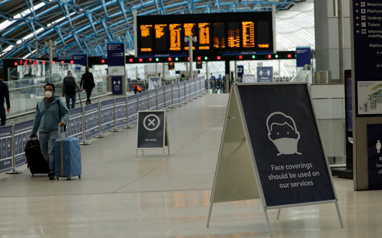 A sign recommending people wear face coverings to help stop the spread of coronavirus is displayed in Waterloo station, London - AP