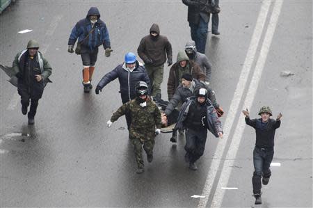 Anti-government protesters run with an injured man on a stretcher in Independence Square in Kiev February 20, 2014. REUTERS/Vasily Fedosenko