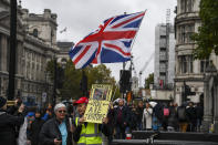 A pro Brexit demonstrator protests outside the Houses of Parliament, holding a placard and a Union flag, in London, Monday, Oct. 21, 2019. The European Commission says the fact that British Prime Minister Boris Johnson did not sign a letter requesting a three-month extension of the Brexit deadline has no impact on whether it is valid and that the European Union is considering the request. (AP Photo/Alberto Pezzali)