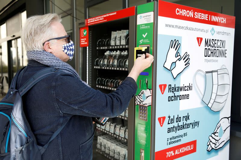 A man uses a vending machine for face masks, gloves and sanitiser during the coronavirus disease (COVID-19) outbreak in Warsaw