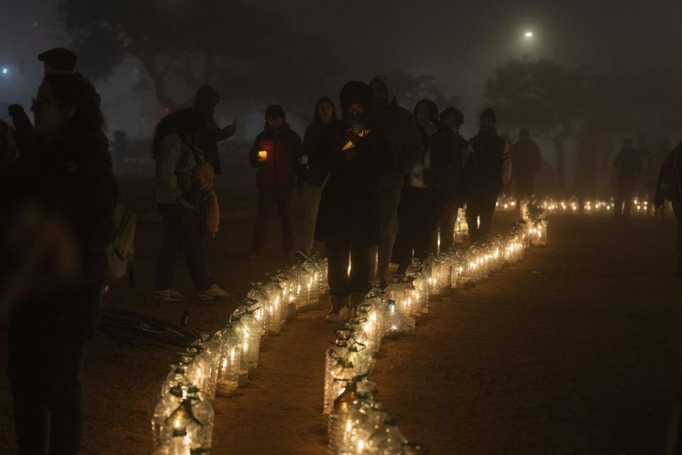 Personas caminan con velas a medianoche en el 50o aniversario del golpe de Estado de 1973, a las afueras del Palacio Legislativo en Montevideo, Uruguay, el martes 27 de junio de 2023. (AP Foto/Matilde Campodónico)