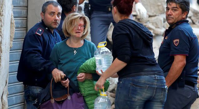 A woman (2nd L) cries after been rescued from her home following a quake in Amatrice, central Italy. Photo: Reuters/Remo Casilli