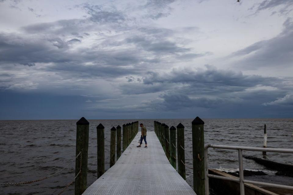 A news reporter walks onto a dock ahead of Hurricane Idalia in Cedar Key.