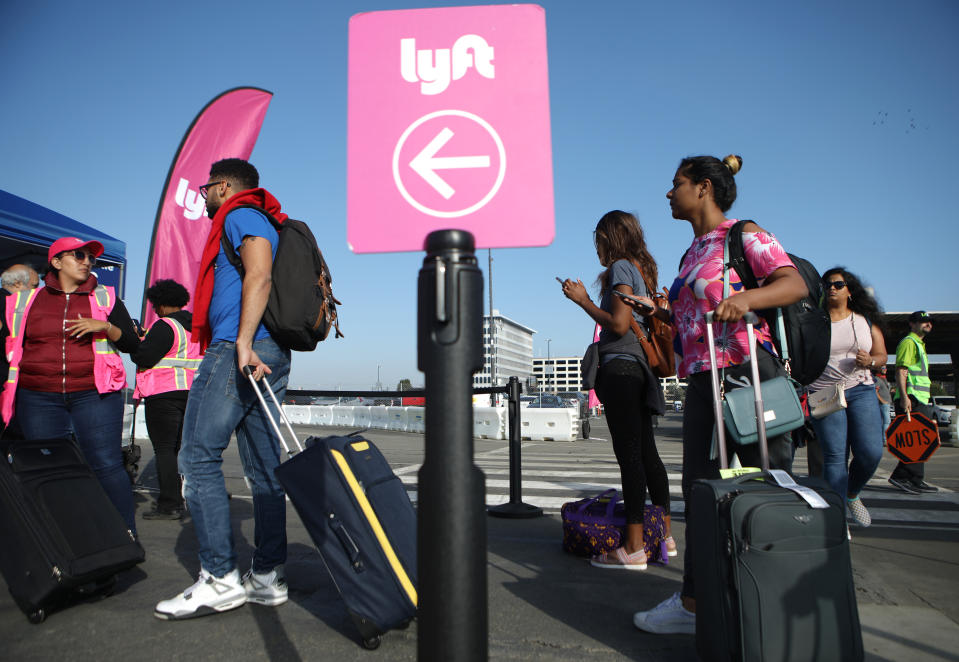 LOS ANGELES, CALIFORNIA - NOVEMBER 06: Arriving passengers wait to board Lyft vehicles at the new 'LAX-it' ride-hail passenger pickup lot at Los Angeles International Airport (LAX) on November 6, 2019 in Los Angeles, California. The airport has instituted a ban on Lyft, Uber and taxi curbside pickups as airport construction increases during a modernization program. Passengers have complained of long wait times and confusion at the pickup area, especially during peak hours. Passengers must depart their terminal and then ride a shuttle bus or walk to the separate pickup lot.  (Photo by Mario Tama/Getty Images)