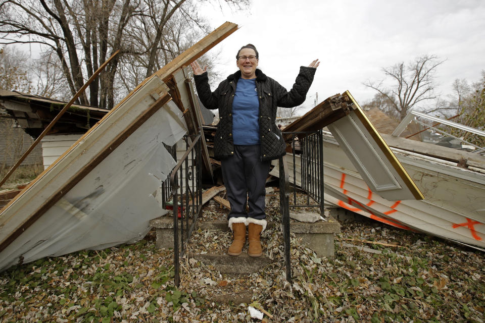 In this photo taken Monday, Nov. 18, 2019, Tammy Kilgore stands on the front porch of her home after it was demolished as part of a voluntary buyout in food-prone Mosby, Mo. Kilgore accepted a $45,000 payment to leave her home of 38 years and has moved to a nearby community. (AP Photo/Charlie Riedel)