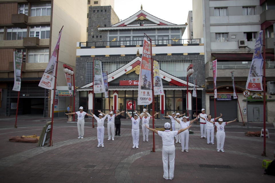 In this Dec. 22, 2018 photo, elderly Japanese immigrants practice radio taiso, a Japanese set of exercises, at the square in Sao Paulo's Asian neighborhood of Liberdade, Brazil. The newspaper that for more than 70 years has been influential in the largest Japanese community outside Japan, has ceased to be printed in Brazil where the first Japanese migrants arrived in 1908, spurring a wave of immigration that grew to about 2 million people. (AP Photo/Victor R. Caivano)