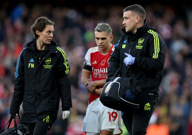 Arsenal’s Leandro Trossard (centre) holds his arm after he fell into the goal post after scoring