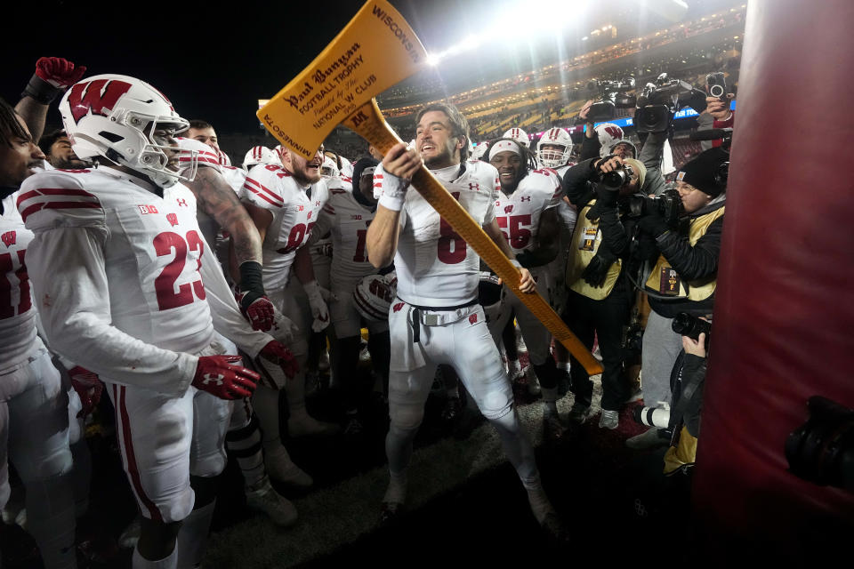 Nov 25, 2023; Minneapolis, Minnesota, USA; Wisconsin quarterback Tanner Mordecai (8) and teammates celebrate with the Paul Bunyan Football Trophy ceremonial axe to act out cutting down the goalposts after defeating the Minnesota Golden Gophers at Huntington Bank Stadium. Wisconsin won 28-14. Mandatory Credit: Mark Hoffman/Milwaukee Journal Sentinel via USA TODAY NETWORK