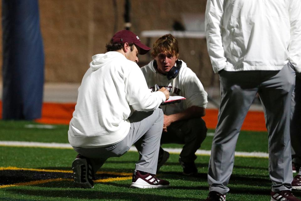 Benedictine assistant coach Caleb Collins talks with fellow coaches during halftime.