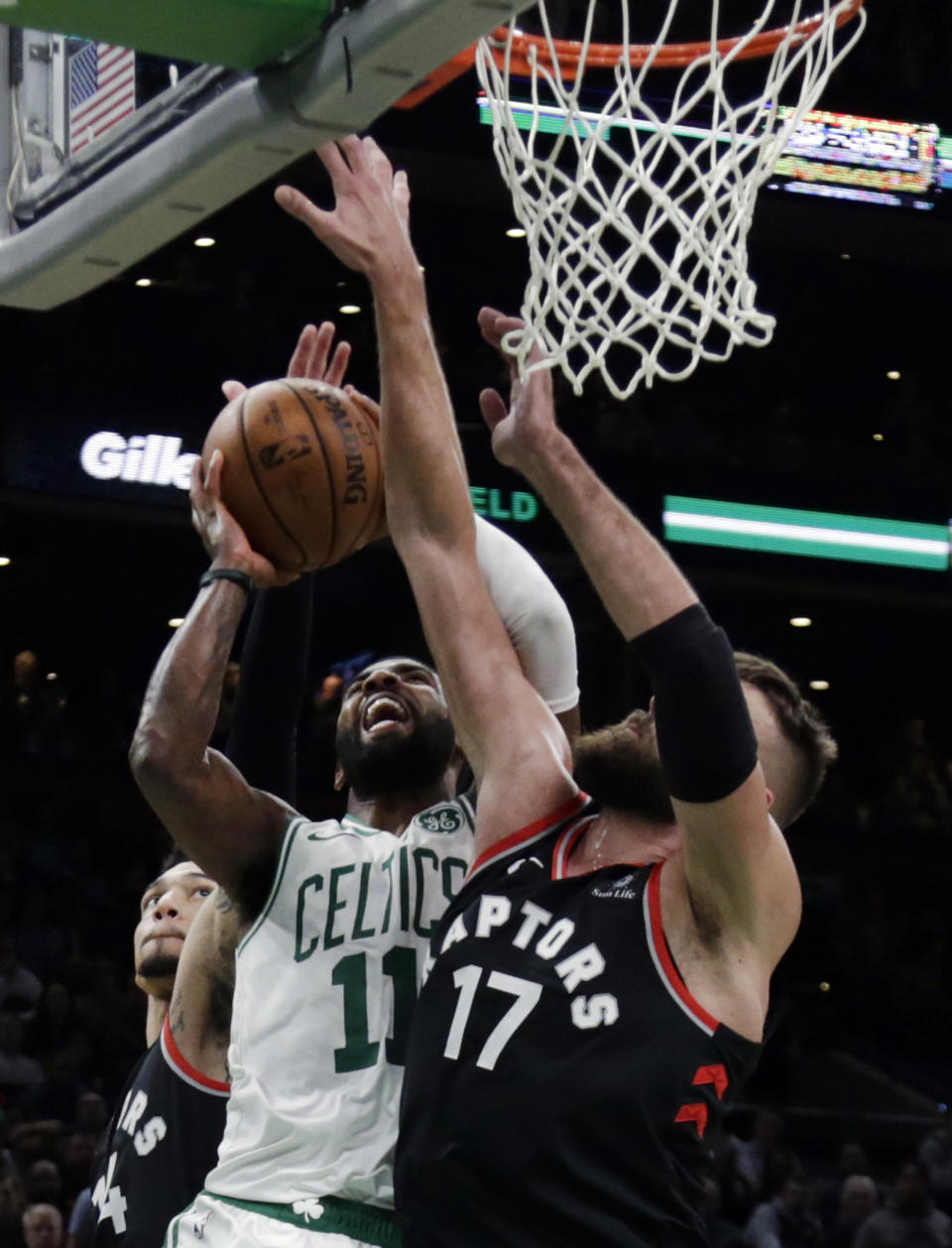 Boston Celtics guard Kyrie Irving (11) scores against Toronto Raptors center Jonas Valanciunas (17) in the fourth quarter of an NBA basketball game, Friday, Nov. 16, 2018, in Boston. Irving totaled 43 points to lead the Celtics to a 123-116 victory in overtime. (AP Photo/Elise Amendola)