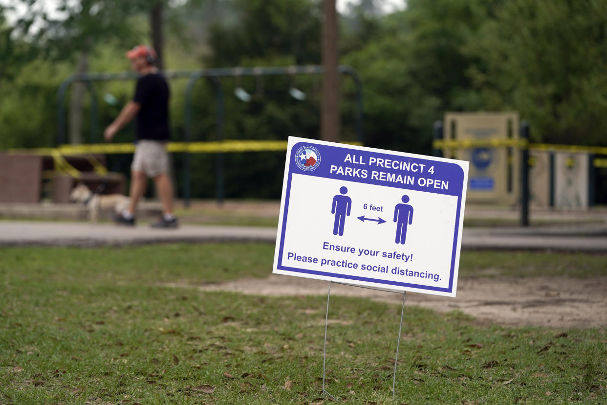 A sign is posted in a park reminding people to practice social distancing Wednesday, March 25, 2020, in Houston. A stay-at-home order was issued Tuesday for Houston and Harris County residents to help fight the spread of COVID-19. The new coronavirus causes mild or moderate symptoms for most people, but for some, especially older adults and people with existing health problems, it can cause more severe illness or death. (AP Photo/David J. Phillip)