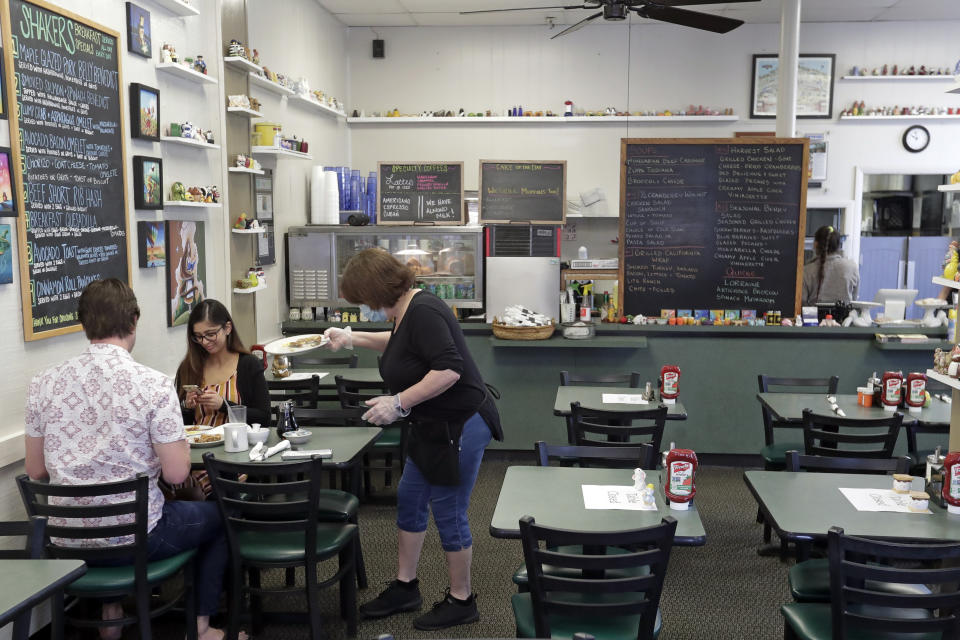 FILE - In this May 4, 2020 file photo, waitress Jill Lawrence. right, waits on customers at Shakers American Cafe Monday in Orlando, Fla. Restaurants, retailers and salons are desperately trying to stay afloat as the U.S. economy reopens in fits and starts after months in a coronavirus lockdown. But billions of dollars allocated by Congress as a lifeline to those very businesses are about to be left on the table when the government's Paycheck Protection Program stops accepting applications for loans Tuesday, June 29. (AP Photo/John Raoux, File)