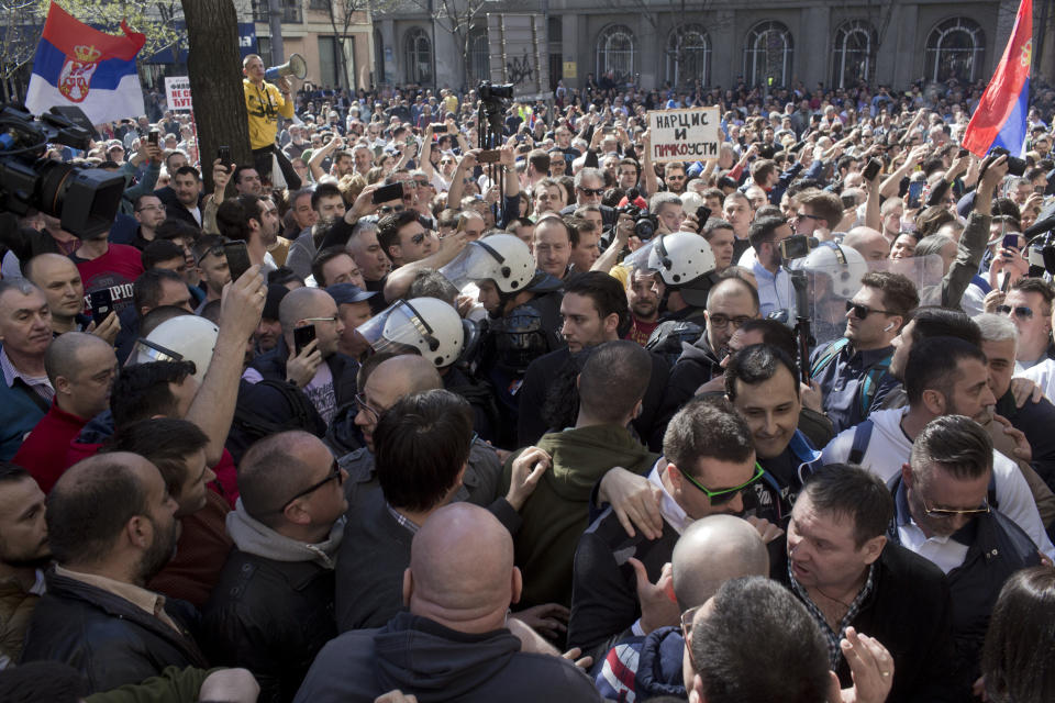 A cordon of riot police officers passes through a crowd of protesters in front of the Serbian presidency building in Belgrade, Serbia, Sunday, March 17, 2019. As Serbian president Aleksandar Vucic held a news conference in the presidency building in downtown Belgrade, thousands of opposition supporters gathered in front demanding his resignation. Skirmishes with riot police were reported, including officers firing tear gas against the protesters who have pledged to form a human chain around the presidency to prevent Vucic from leaving the building. (AP Photo/Marko Drobnjakovic)