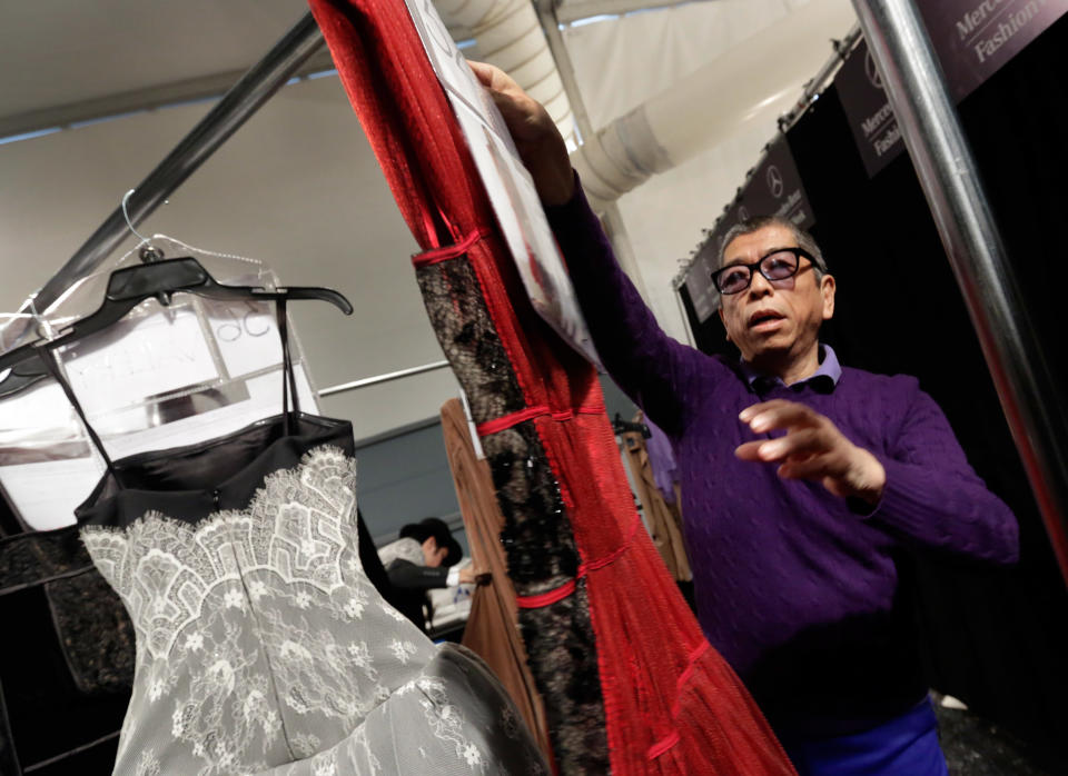 Designer Tadashi Shoji hangs one of the dresses backstage before his Fall 2013 collection was modeled during Fashion Week in New York, Thursday, Feb. 7, 2013. (AP Photo/Richard Drew)
