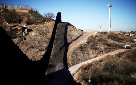 A US border patrol agent patrols the US border with Mexico in Nogales, Arizona - Credit: REUTERS/Lucy Nicholson