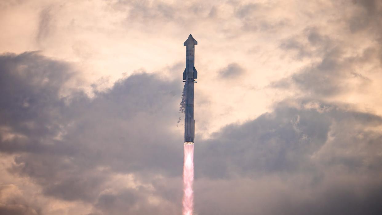  A large silver rocket flies through a golden morning sky. 