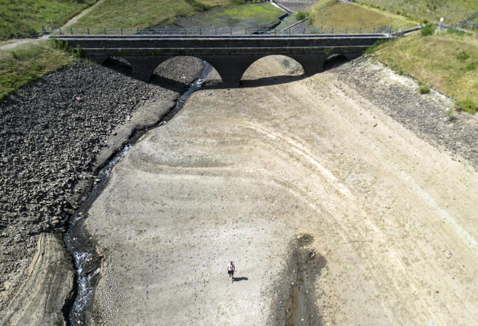 A man walks a dry bank of a tributary to the Dowry Reservoir close to Oldham on July 18 (Danny Lawson/PA) (PA Wire)