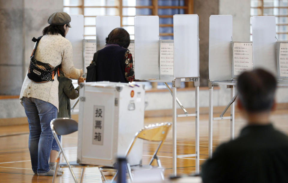 People prepare to vote in a referendum at a polling station in Naha, Okinawa, Japan, Sunday, Feb. 24, 2019. The people of Okinawa are voting on a plan for a U.S. military base relocation in the referendum that will send a message on how they feel about housing American troops in Japan, who many see as a burden on the group of tiny southwestern islands. (Kyodo News via AP)