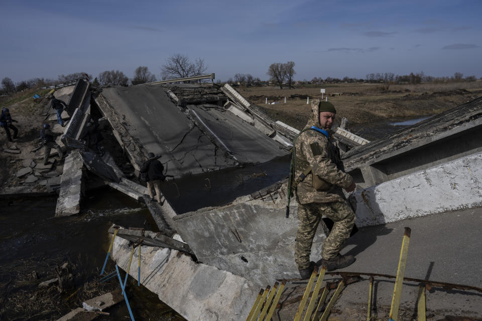 A soldier stands on a bridge destroyed by the Ukrainian army to prevent the passage of Russian tanks near Brovary, in the outskirts of Kyiv, Ukraine, Monday, March 28, 2022. (AP Photo/Rodrigo Abd)