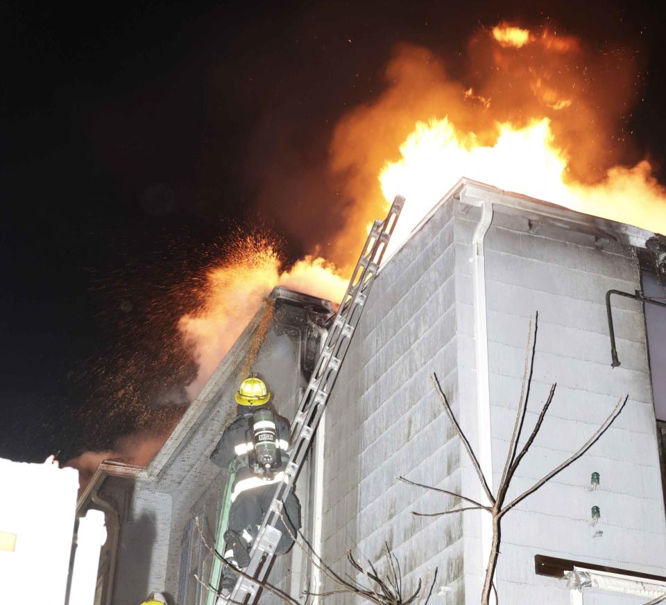 Firefighters attack a blaze Friday night on the roof of 25 Wayne St. in Worcester.