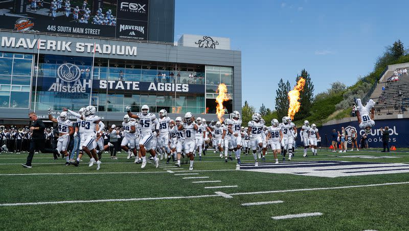 The Utah State Aggies storm the field before playing the UConn Huskies at the Maverik Stadium in Logan on Saturday, Aug. 27, 2022.