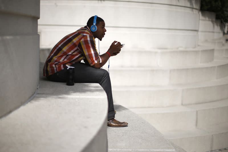 FILE PHOTO: A man with Beats headphones listens to music on an iPhone in Los Angeles