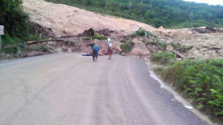 A supplied image shows locals inspecting a landslide and damage to a road located near the township of Tabubil after an earthquake that struck Papua New Guinea's Southern Highlands, February 26, 2018. Jerome Kay/Handout via REUTERS