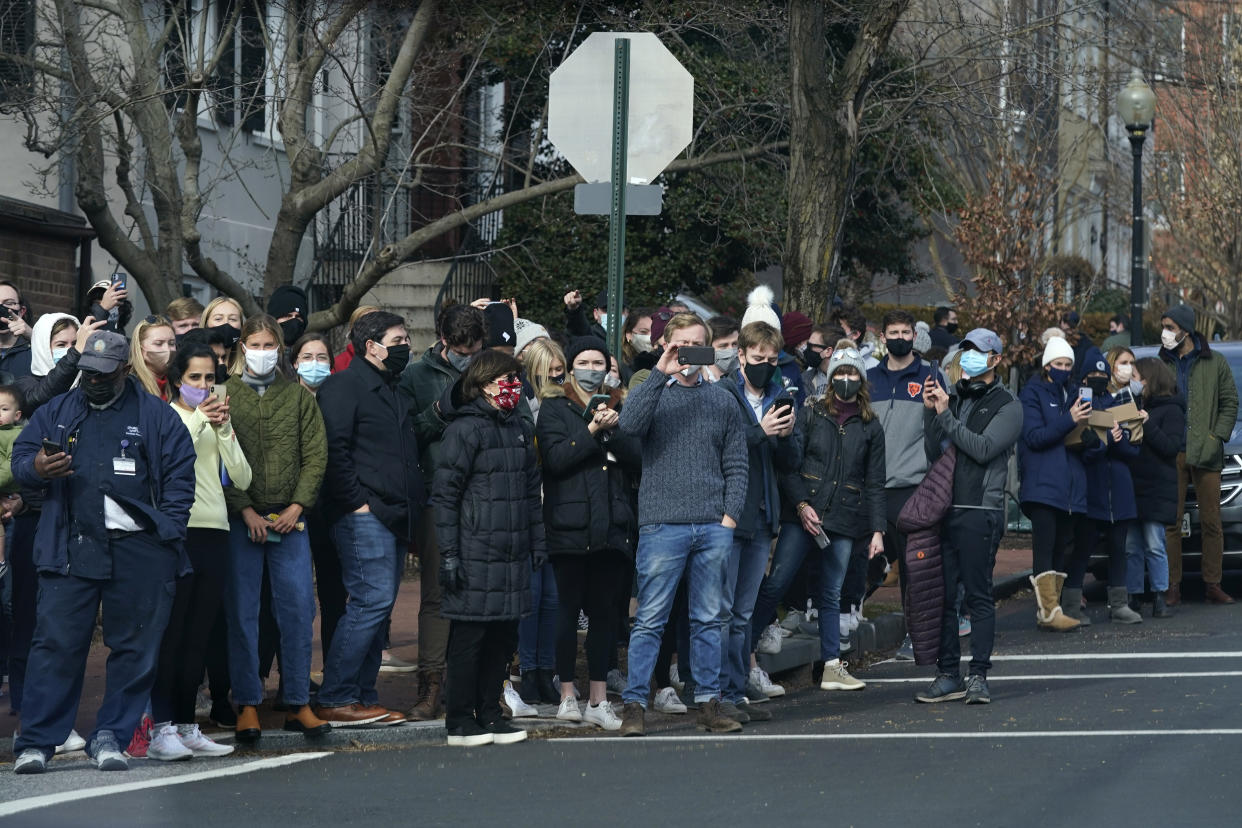 People gather to watch as President Joe Biden's motorcade departs Holy Trinity Catholic Church, Sunday, Jan. 24, 2021, in the Georgetown neighborhood of Washington. (AP Photo/Patrick Semansky)