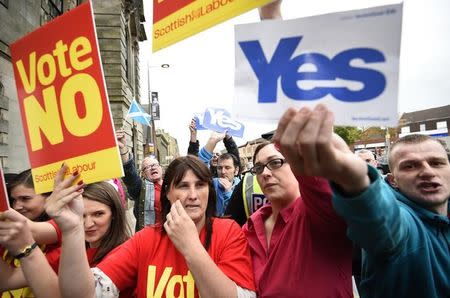 Pro and anti-independence supporters wave posters outside a campaign event in favour of the union in Clydebank, Scotland, September 16, 2014. REUTERS/Dylan Martinez
