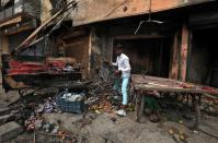 A shopkeeper salvages his belongings from his damaged shop that was set on fire by a mob in a riot affected area after clashes erupted between people demonstrating for and against a new citizenship law in New Delhi