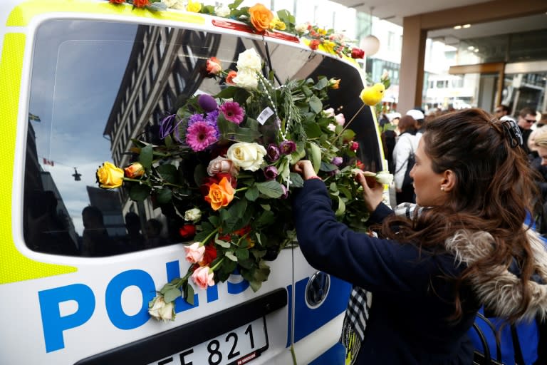 A woman places flowers on a police car in Stockholm, close to the point where a truck drove into a department store on April 7