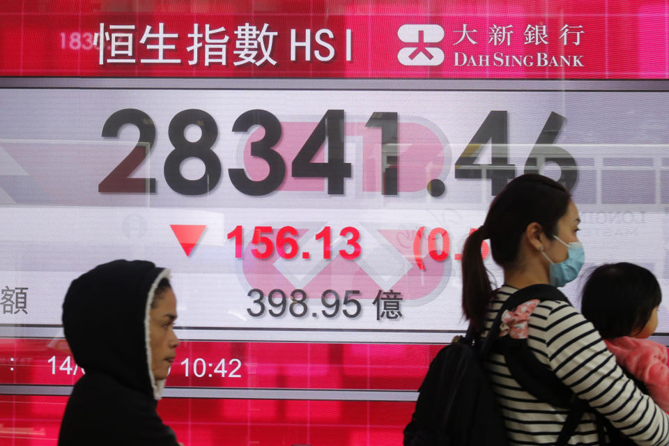 People walk past an electronic board showing Hong Kong share index outside a bank in Hong Kong, Thursday, Feb. 14, 2019. Asian stocks were mostly lower on Thursday as China and the U.S. kicked off two days of trade negotiations in Beijing. (AP Photo/Kin Cheung)