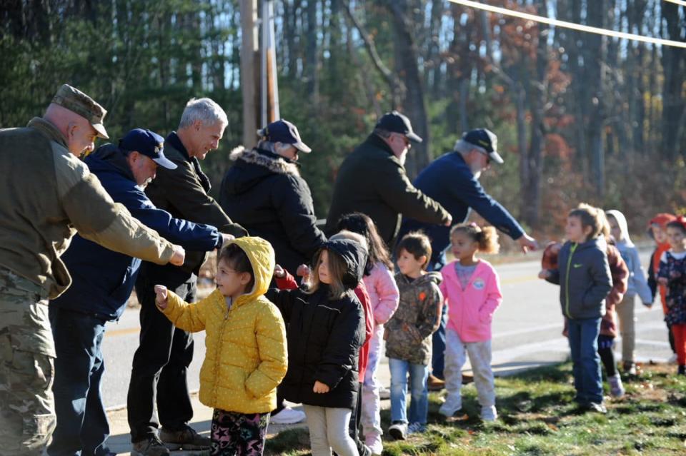 Students at the Chamberlain School line up to fist bump local veterans who attended a flag raising ceremony at the school on Tuesday.