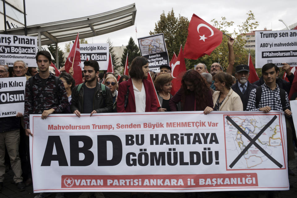 Members of a Turkish political party hold national flags and a banner that reads "The USA is buried in this map!" during a protest near the U.S. embassy in Ankara, Turkey, Tuesday, Oct. 8, 2019. Turkey's vice president Fuat Oktay says his country won't bow to threats in an apparent response to U.S. President Donald Trump's warning to Ankara about the scope of its planned military incursion into Syria. (AP Photo/Burhan Ozbilici)