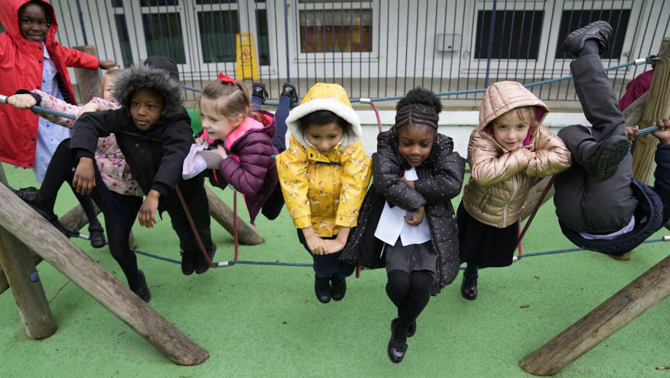 Faith, left, with some of her fellow pupils Julia, Nana, Yaw, Alexandra, Leandra, and Amariah, right play on a rope swing at the Holy Family Catholic Primary School during a break, in Greenwich, London, Wednesday, May 19, 2021. Holy Family, like schools across Britain, is racing to offset the disruption caused by COVID-19, which has hit kids from low-income and ethnic minority families hardest. (AP Photo/Alastair Grant)