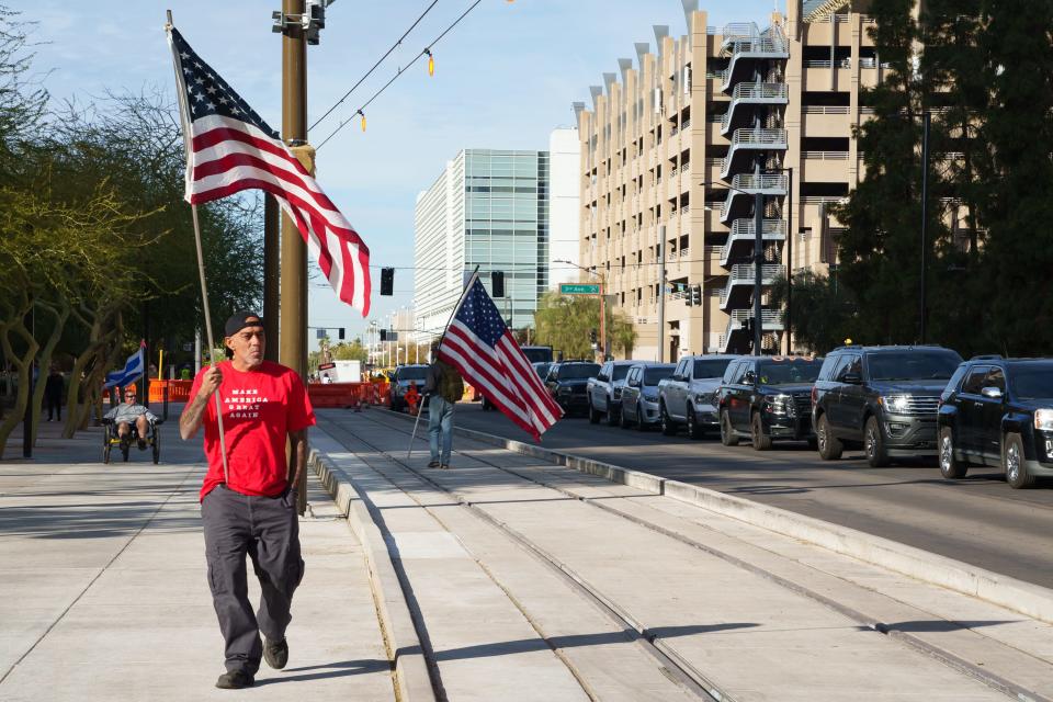 Protestors carry flags outside the Maricopa County Board of Supervisors Auditorium during the Maricopa County election certification on Nov. 28, 2022 in Phoenix, Ariz.