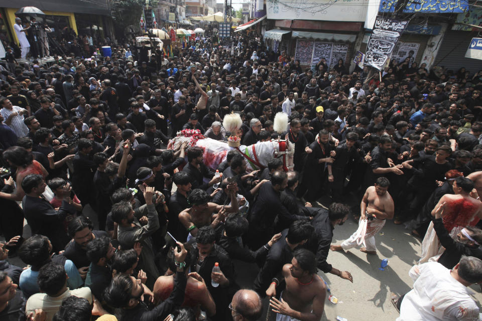 Shiite Muslims touch a horse, that symbolises the horse that carried Imam Hussein during the battle of Karbala, during a Muharram procession, in Lahore, Pakistan, Monday, Aug. 8, 2022. Muharram, the first month of the Islamic calendar, is a month of mourning for Shiites in remembrance of the death of Hussein, the grandson of the Prophet Muhammad, at the Battle of Karbala in present-day Iraq in the 7th century. (AP Photo/K.M. Chaudary)