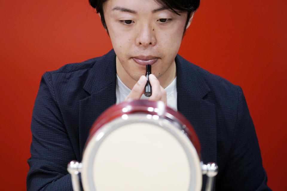 Naruhiko Ito, assistant brand manager of Brand Shiseido Group, demonstrates the brand's latest lip balm for men in Tokyo Thursday, April 15, 2021. A large personal care company, Shiseido, says one of its male makeup lines has seen double-digit growth during the coronavirus pandemic. Company officials give a similar reason: Men, confronted with the sight of their faces repeatedly during online meetings, want to improve what they see. (AP Photo/Eugene Hoshiko)