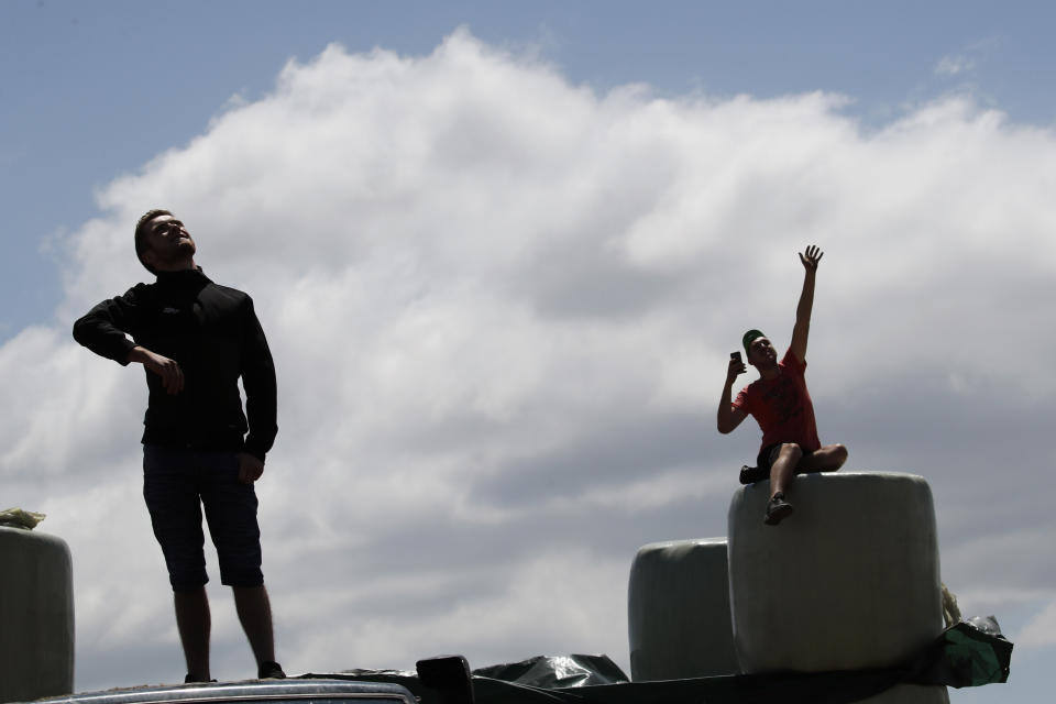 A spectator waves to the helicopter with the live TV feed The pack rides during the tenth stage of the Tour de France cycling race over 217 kilometers (135 miles) with start in Saint-Flour and finish in Albi, France, Monday, July 15, 2019. (AP Photo/ Christophe Ena)