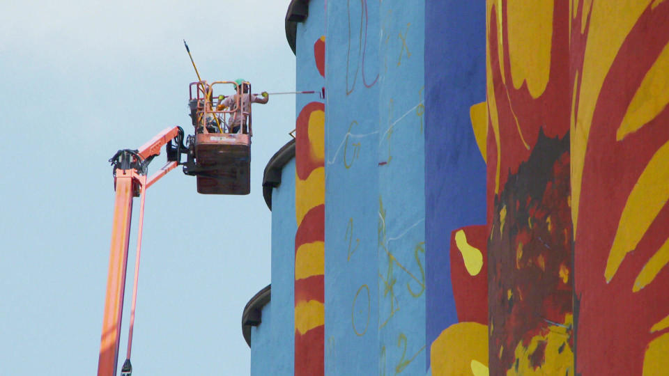 Work proceeds on artist Gabe Gault's mural along the Toledo, Ohio waterfront, painted onto grain solos. / Credit: CBS News